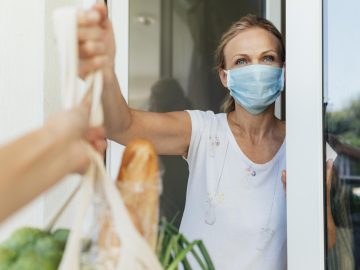 woman-with-medical-mask-picking-up-her-groceries-in-self-isolation