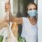 woman-with-medical-mask-picking-up-her-groceries-in-self-isolation